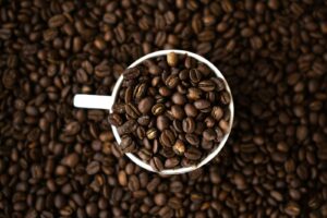 a cup filled with coffee beans on top of a pile of coffee beans